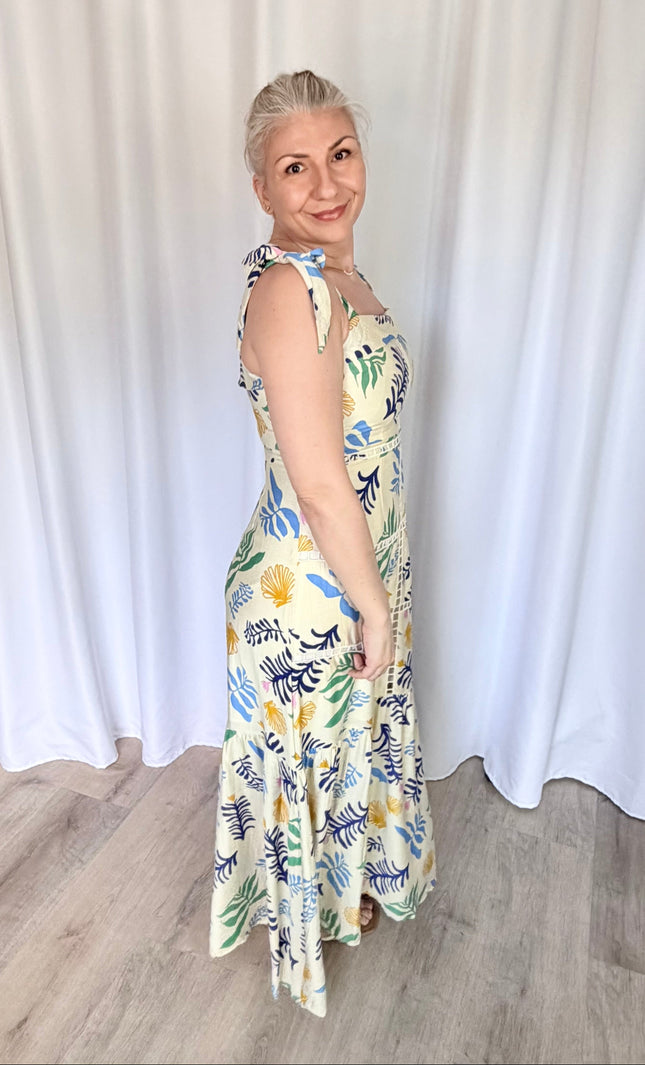 Side profile shot of the reef print maxi dress, emphasizing the clean fit of the upper bodice, the adjustable shoulder ties, and the graceful silhouette of the long tiered skirt.
