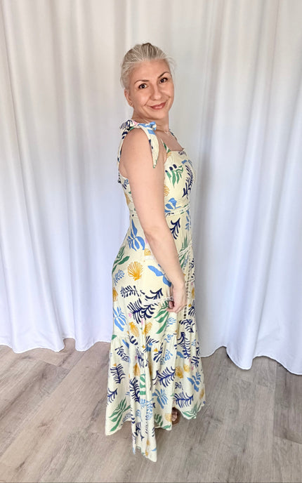 Side profile shot of the reef print maxi dress, emphasizing the clean fit of the upper bodice, the adjustable shoulder ties, and the graceful silhouette of the long tiered skirt.