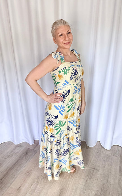 Side profile shot of the reef print maxi dress, emphasizing the clean fit of the upper bodice, the adjustable shoulder ties, and the graceful silhouette of the long tiered skirt.
