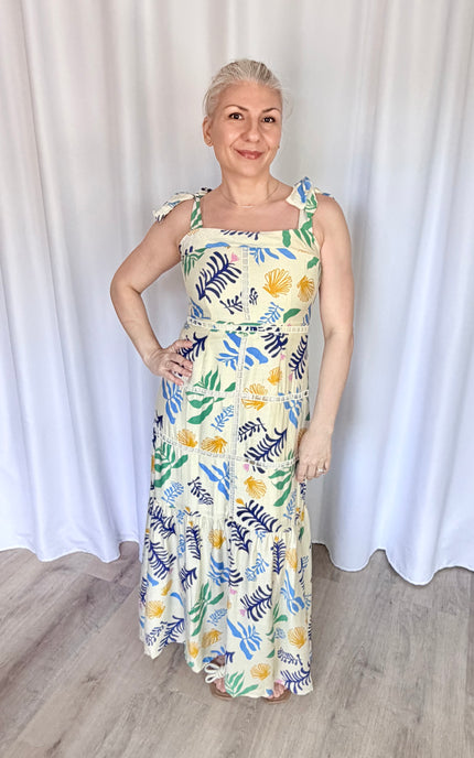 A 5'6" model wearing a size Medium Marina Maxi Dress, styled for an approachable, effortless, and elegant coastal getaway look.