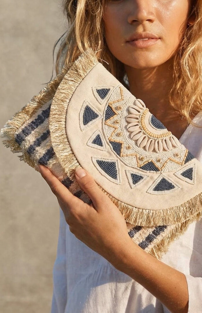 Hand‑beaded navy and cream mandala clutch with soft fringe trim and oversized envelope silhouette.