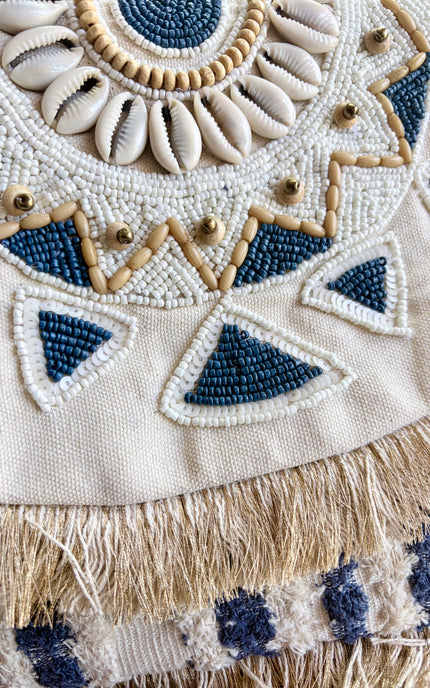 Oversized navy and cream beaded clutch with mandala pattern and fringe trim displayed on a neutral background.