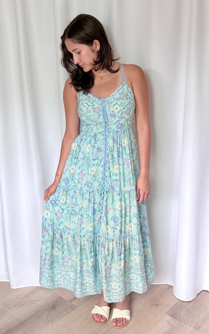 A relaxed, natural shot of the model holding out one side of the dress to show off the lightweight drape and effortless movement of the fabric.