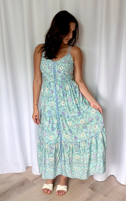 A relaxed, natural shot of the model holding out one side of the dress to show off the lightweight drape and effortless movement of the fabric.