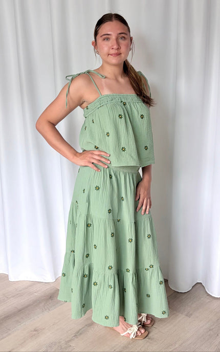 Model wearing a romantic floral embroidered cotton gauze matching set styled for summer, featuring a tiered midi skirt and tie-shoulder tank