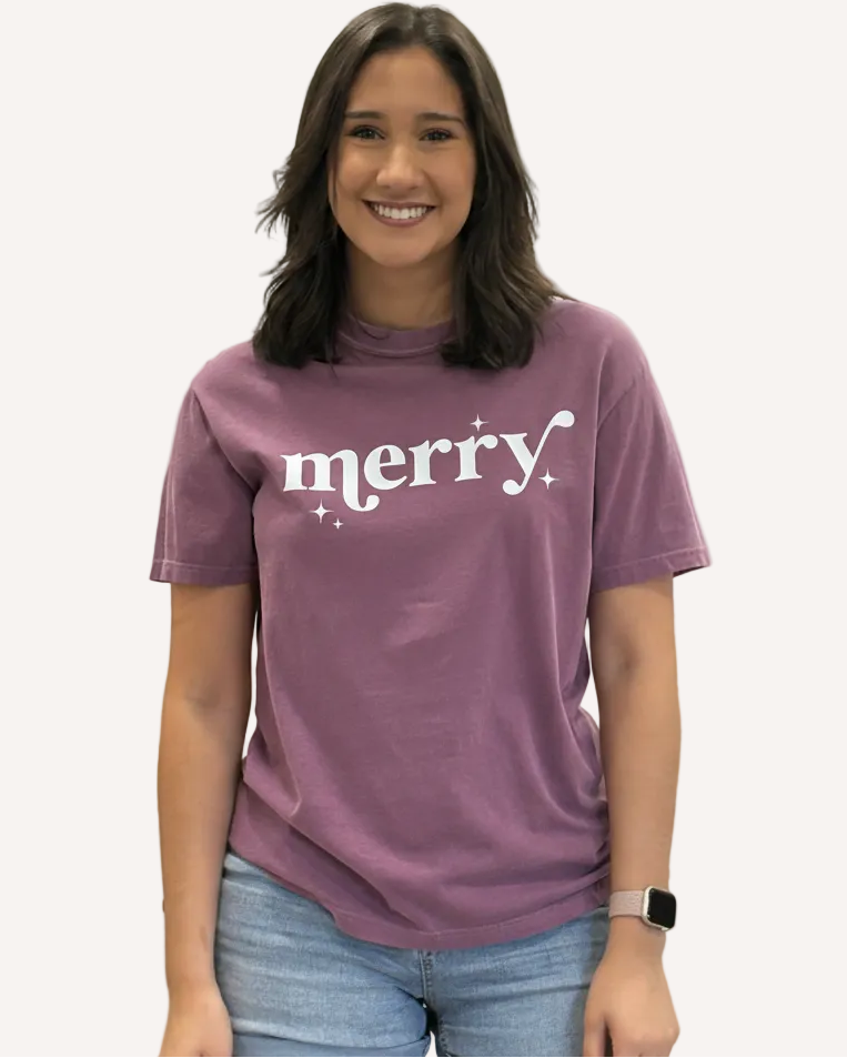 Person wearing a purple t-shirt with 'merry' text on a plain background