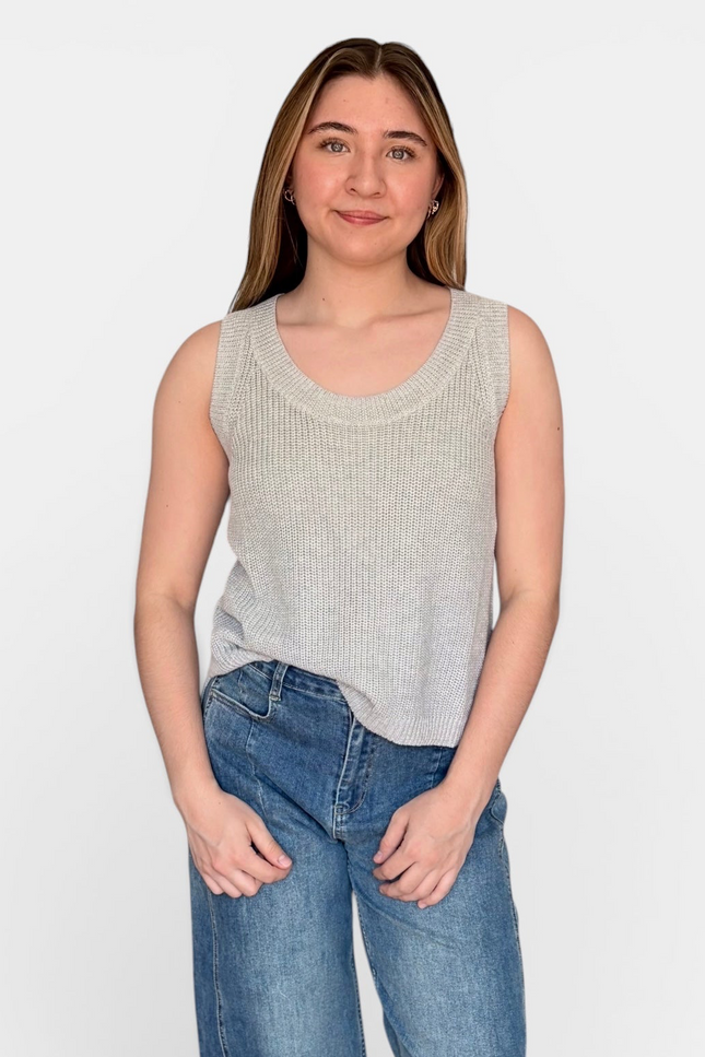 A woman modeling a light gray ribbed knit sleeveless scoop-neck tank top with blue jeans, standing against a plain white studio background.