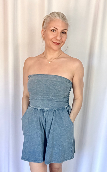 Woman wearing a strapless denim dress against a white curtain background