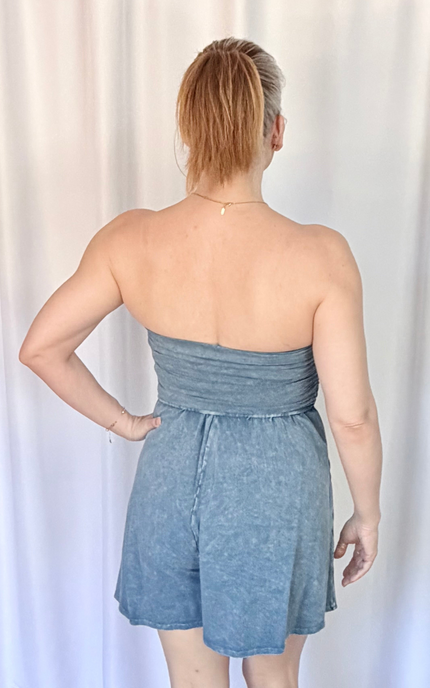 Woman wearing a strapless denim dress against a white curtain background