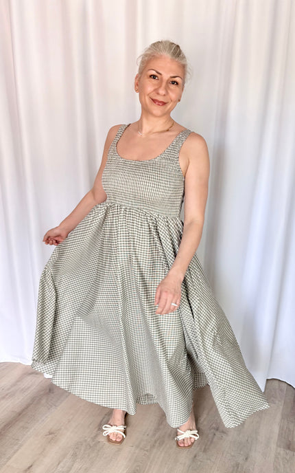 A dynamic shot of a model mid-twirl, showcasing the full flare, beautiful movement, and elegant sweep of the full-length gingham maxi skirt.