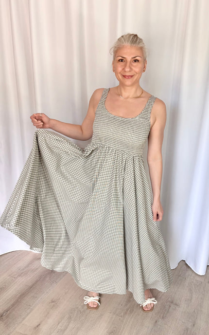 A 5'6" model wearing the timeless gingham Nora Maxi Dress, styled for an approachable, classic, and feminine warm-weather look.