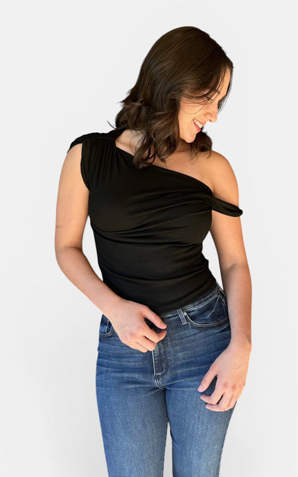 Woman wearing a black asymmetrical off shoulder twist front fitted knit top with denim jeans.