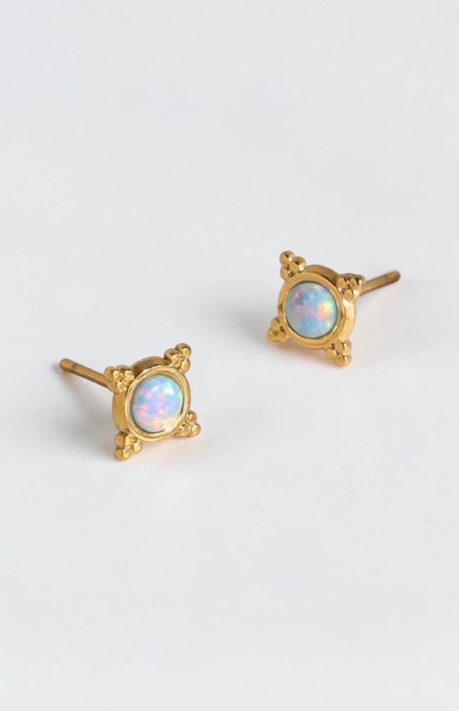 A clear, focused close-up of the pair of gold PVD plated stainless steel studs, showcasing the 3.9mm round synthetic opal stone and the delicate beaded frame.