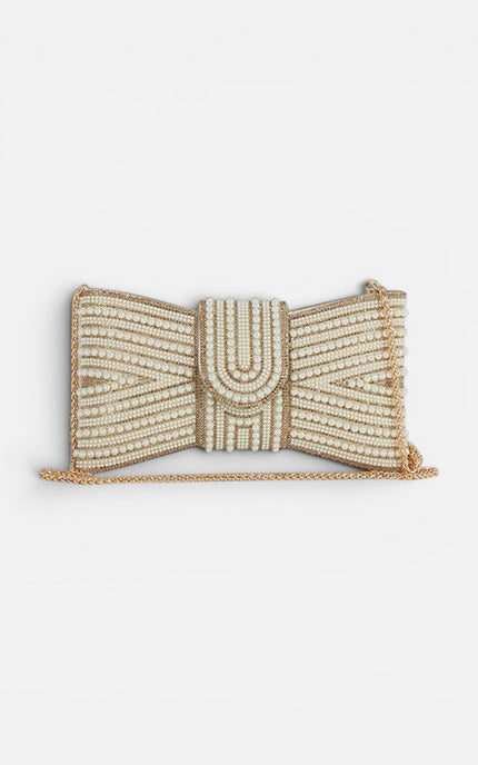 Front view of a cream rectangular clutch featuring a large, ornate bow made of white pearls set in a polished gold-tone frame.