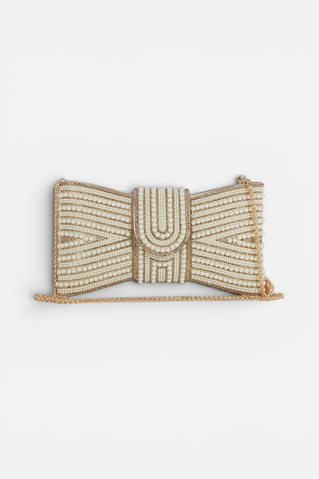 Front view of a cream rectangular clutch featuring a large, ornate bow made of white pearls set in a polished gold-tone frame.