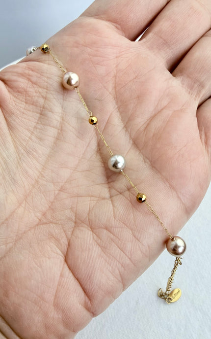 Pearl station bracelet displayed in the palm of a hand showing delicate gold bead accents.