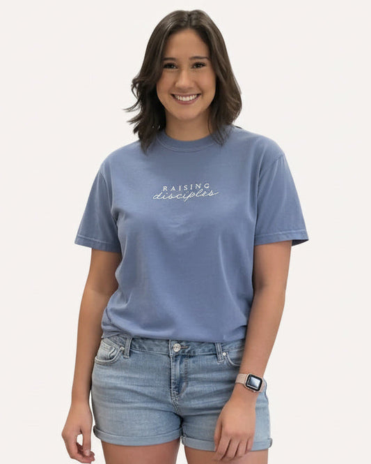 Person wearing a blue t-shirt with 'Raising disciples' text 