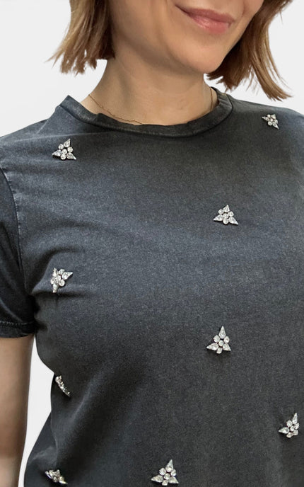 Close-up of a woman wearing a dark gray short-sleeve t-shirt with small silver floral embellishments scattered across the front.