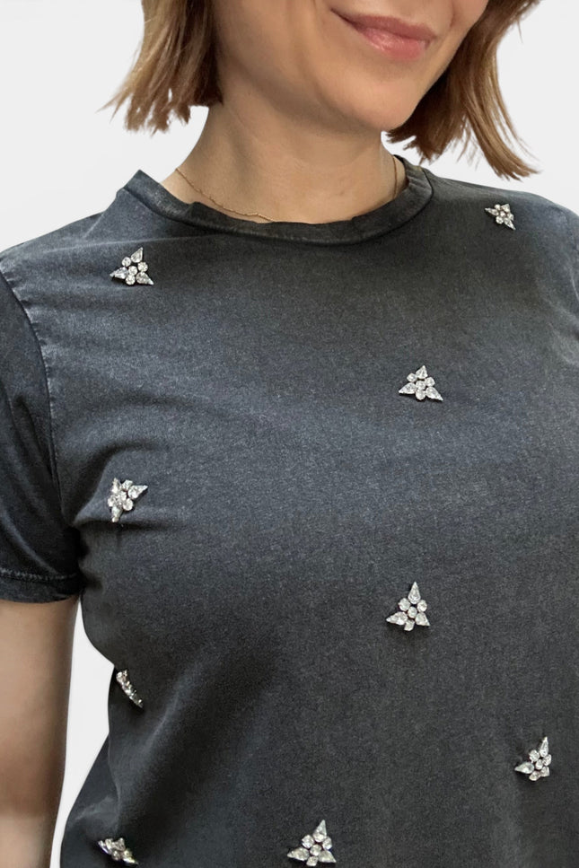 Close-up of a woman wearing a dark gray short-sleeve t-shirt with small silver floral embellishments scattered across the front.