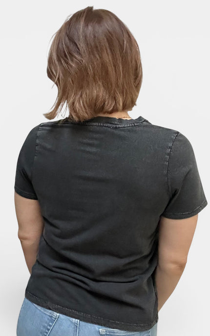 A woman viewed from behind wearing a faded black short-sleeve t-shirt and light blue jeans against a plain white background.
