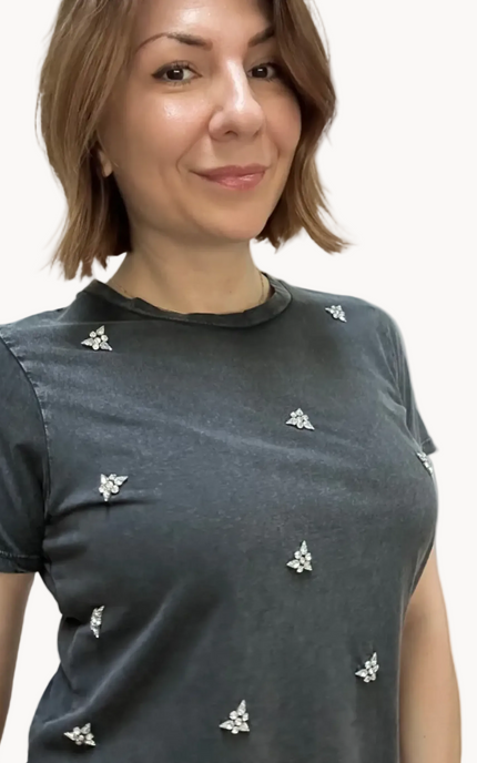 Woman wearing a dark gray t-shirt with white floral patterns on a plain background