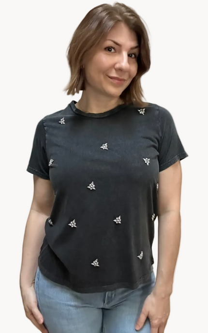 Woman wearing a black t-shirt with white patterns on a plain background