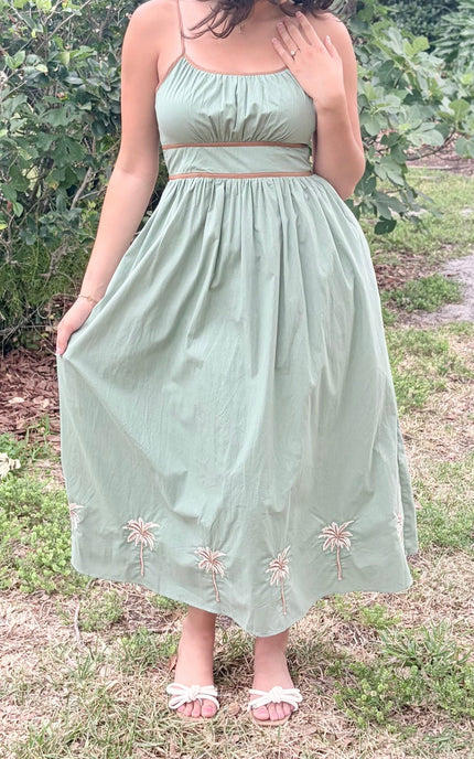 Woman wearing a light green dress with floral embroidery in an outdoor setting