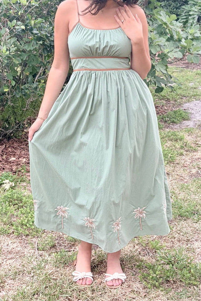 Woman wearing a light green dress with floral embroidery in an outdoor setting