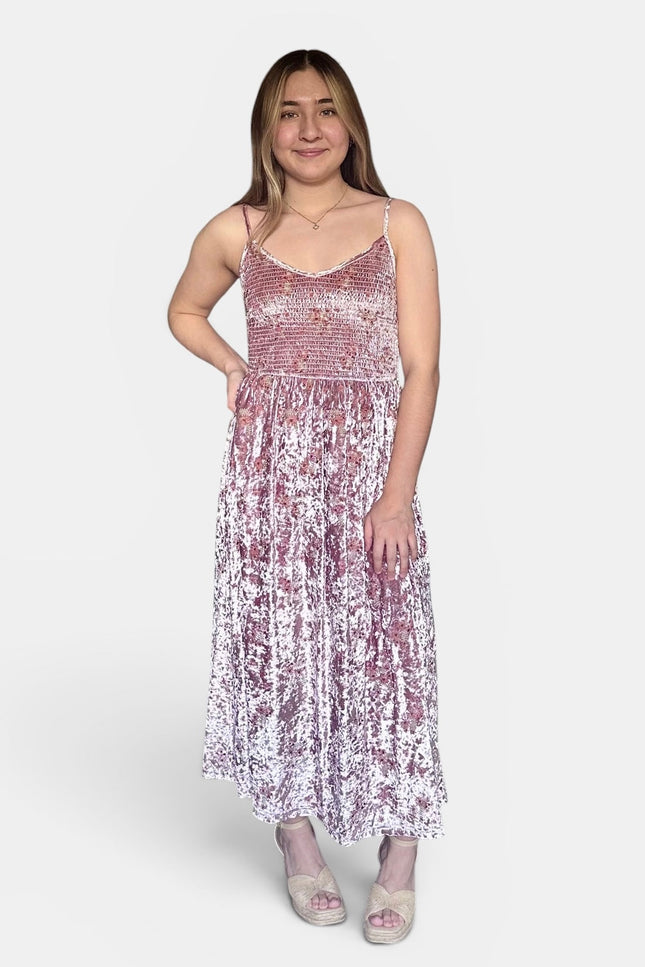 Sleeveless midi dress with thin straps, a smocked bodice, and a pleated skirt covered in pink and white sequins, set against a plain light gray studio background.