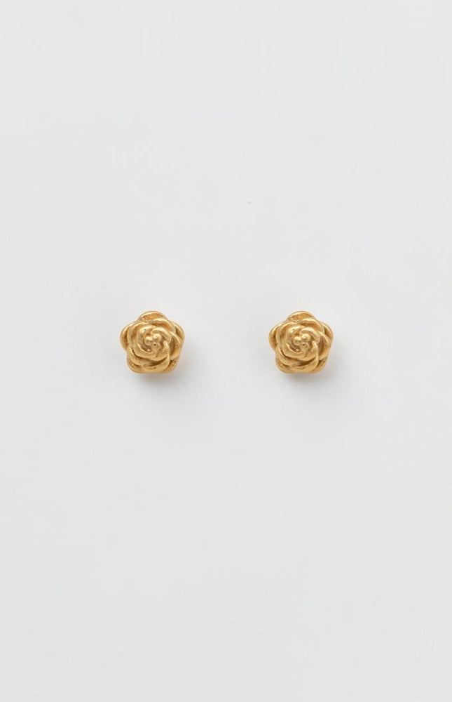 A pair of sculpted gold rose blossom stud earrings resting on a clean, soft background, showcasing their detailed texture and vintage-inspired charm.