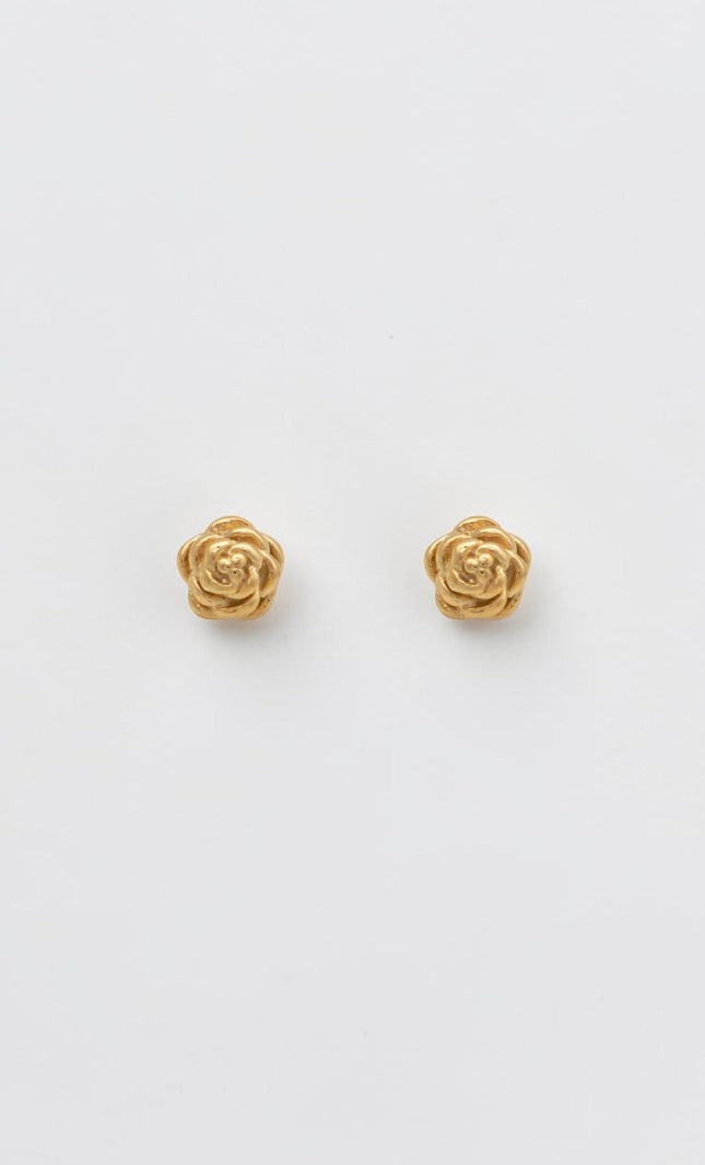 A pair of sculpted gold rose blossom stud earrings resting on a clean, soft background, showcasing their detailed texture and vintage-inspired charm.