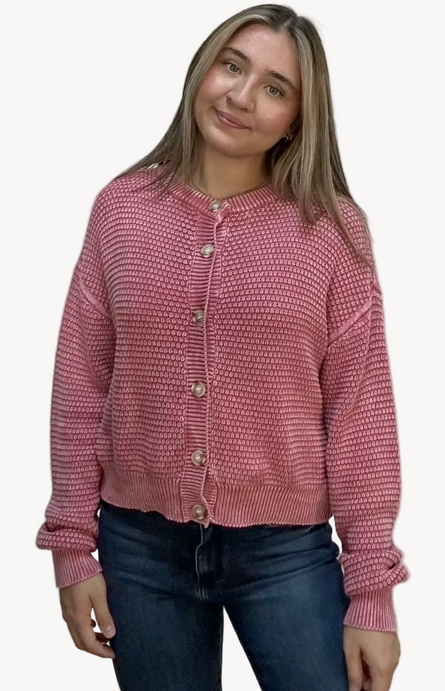 Woman wearing a pink textured cardigan against a plain background