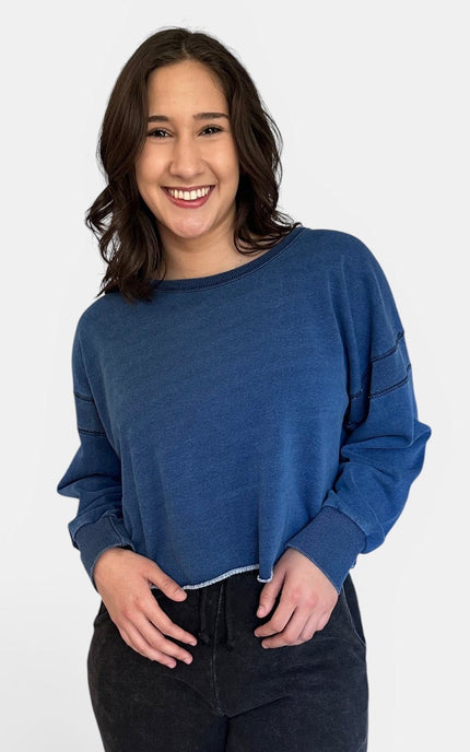 Front view of oversized denim wash sweatshirt with wide neckline and long sleeves.