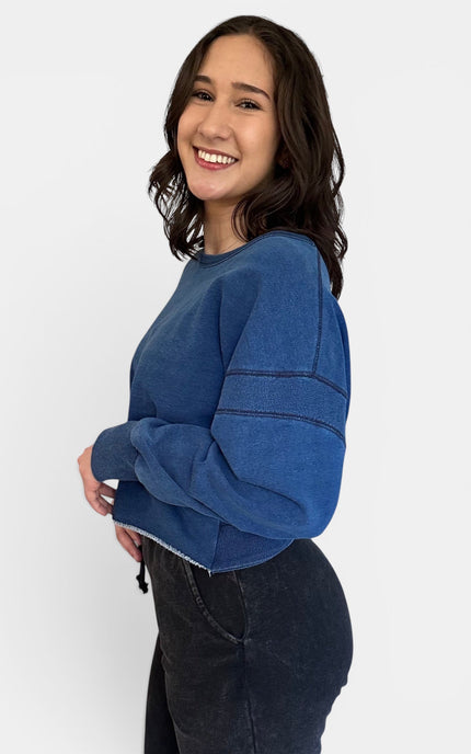 Women's denim wash sweatshirt shown from the side with dropped shoulders.