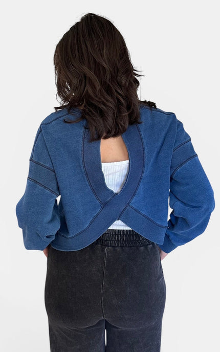 Back view of oversized denim wash sweatshirt featuring an open cutout back.