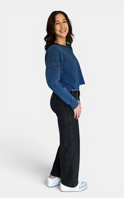 Side angle of relaxed oversized denim wash sweatshirt with open back design.