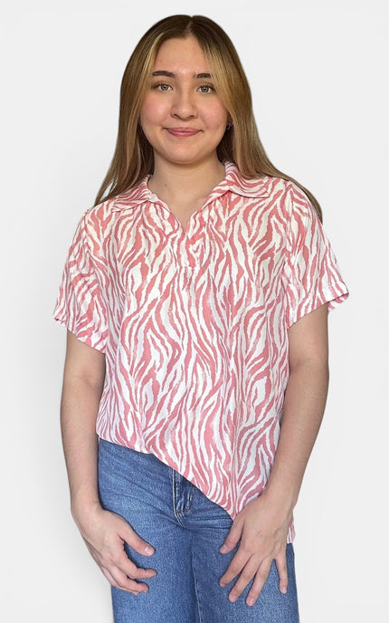 Short-sleeve collared button-up shirt with a pink and white zebra-like abstract pattern, paired with blue jeans, against a plain light gray background.
