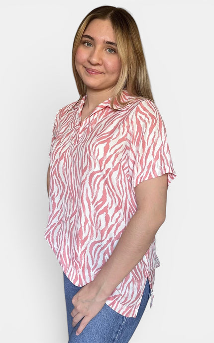 Short-sleeve button-up shirt with a pink and white zebra print, paired with blue jeans, against a plain light gray background.