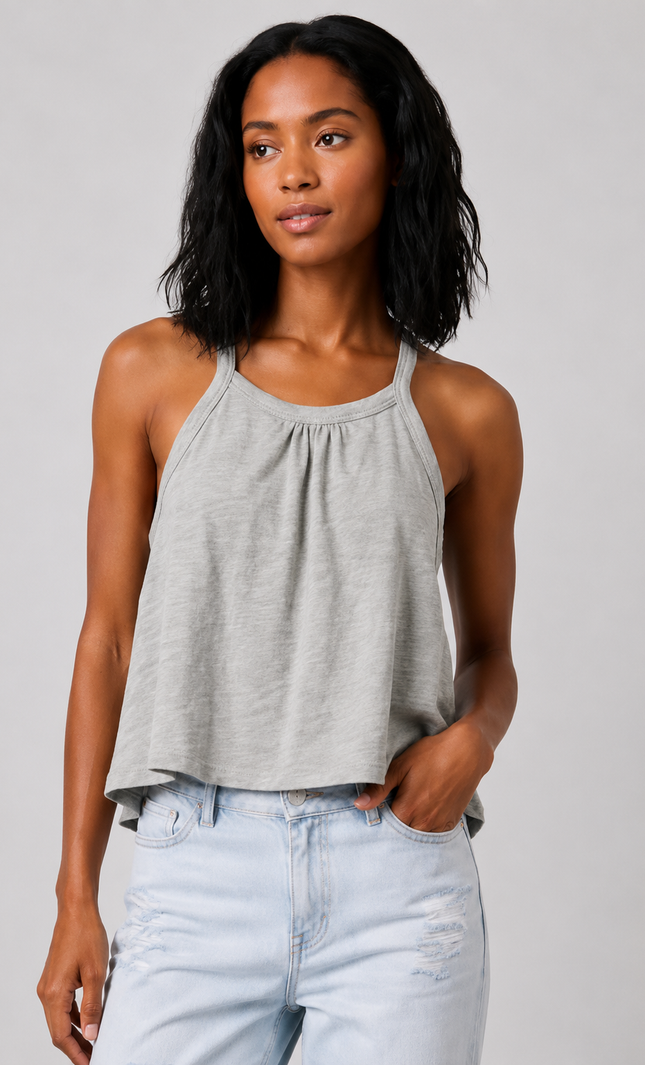 Woman wearing a sage gray tank top and light blue jeans against a plain background