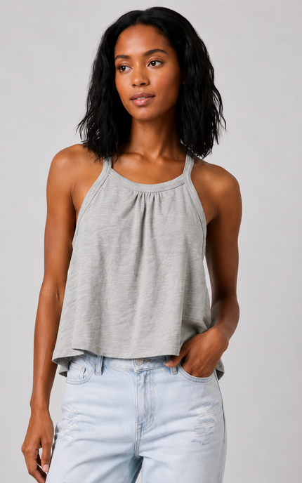 Woman wearing a sage gray tank top and light blue jeans against a plain background
