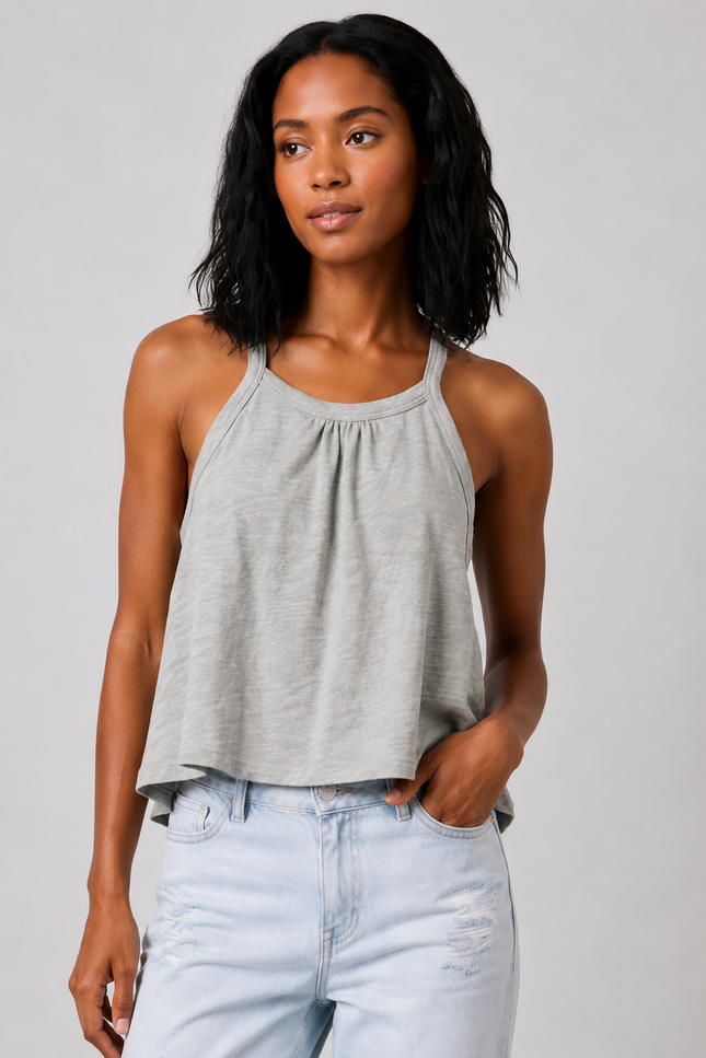 Woman wearing a sage gray tank top and light blue jeans against a plain background