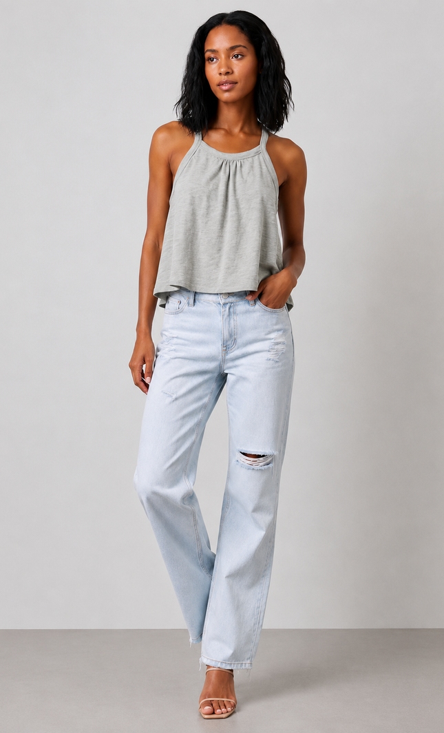 Woman wearing a sage gray halter top and light blue jeans against a plain background