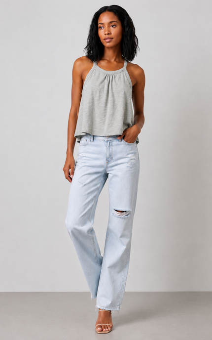 Woman wearing a sage gray halter top and light blue jeans against a plain background
