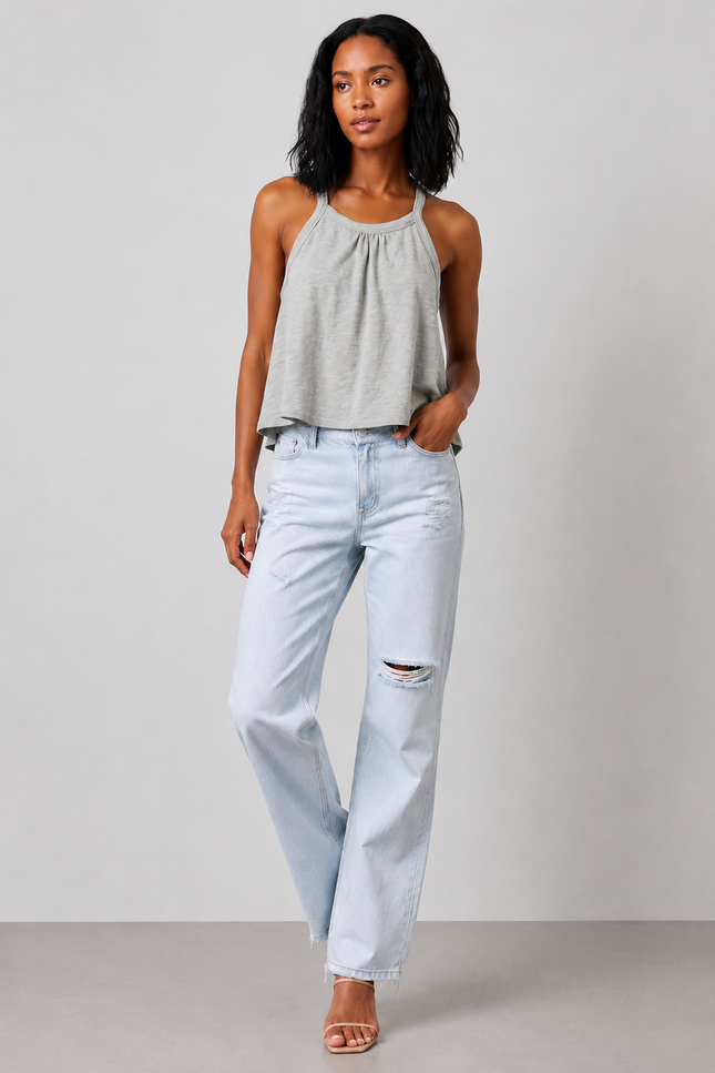 Woman wearing a sage gray halter top and light blue jeans against a plain background