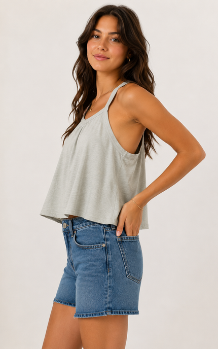 Side view of a woman wearing a sage green cotton racerback swing tank featuring a relaxed swing silhouette and breathable fabric.