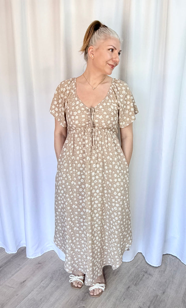 Woman wearing a floral dress standing against a white curtain