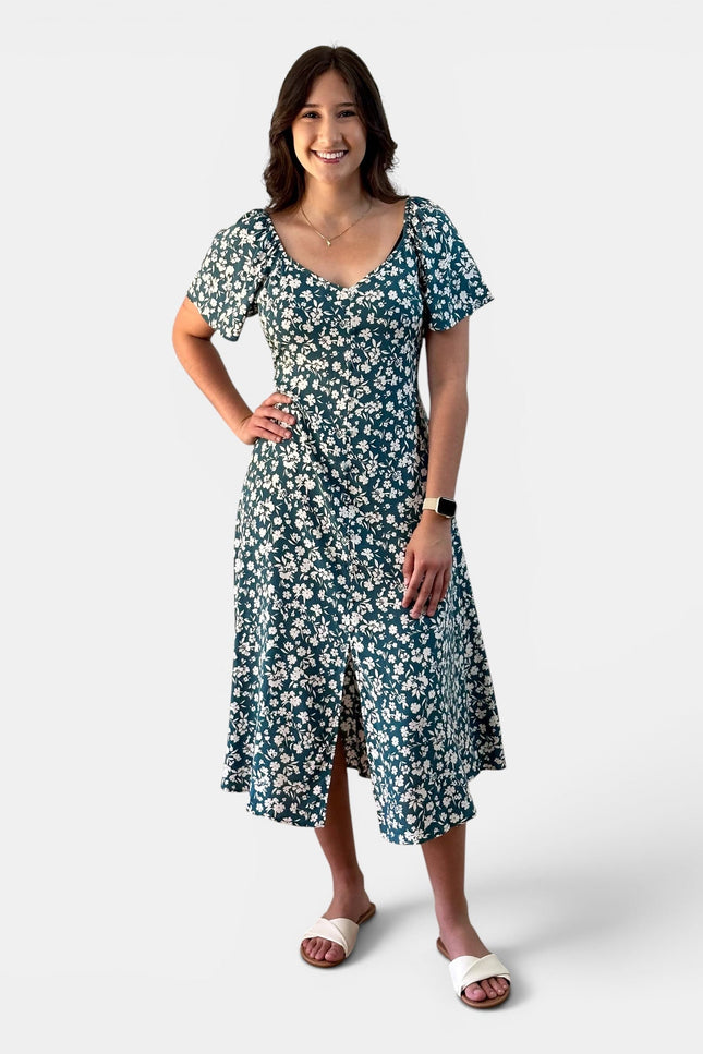 Woman wearing a teal floral midi dress with a princess neckline, button front, and flared sleeves.
