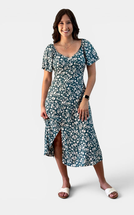 Front view of a teal floral midi dress with flared sleeves and a flowy silhouette.