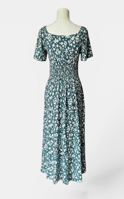 Back view of a teal floral midi dress with flared sleeves and a flowing midi-length skirt.