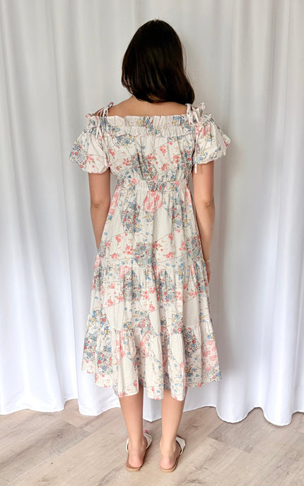 Back view of floral print off-shoulder midi dress showing tiered skirt silhouette and adjustable shoulder straps